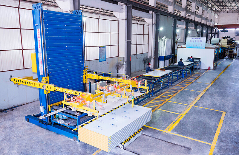 Factory workshop photo: production equipment, stacked boards, and workers in the workshop